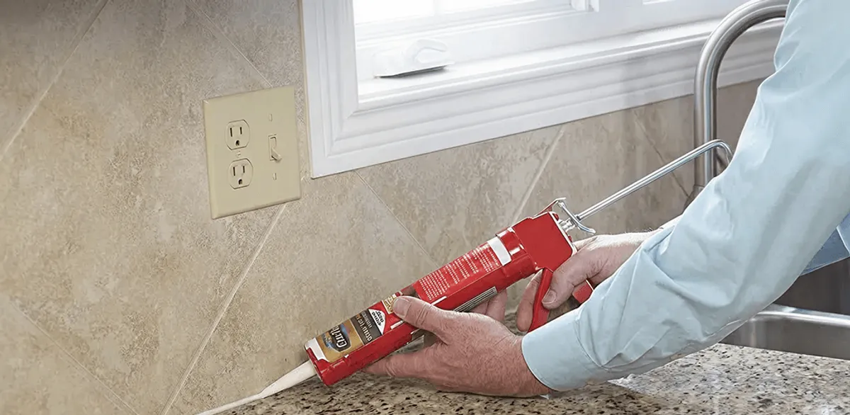 Handyman applying caulk along a kitchen backsplash and countertop seam in Portland, OR