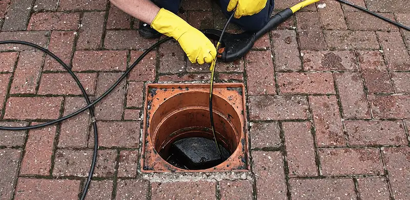Drain cleaning technician using a drain snake to clear a clogged drain in Portland, OR