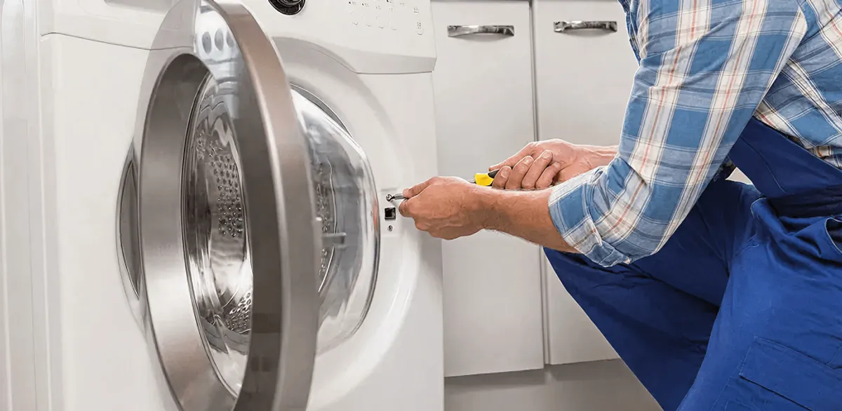 Handyman repairing a clothes dryer and checking electrical connections in Portland, OR