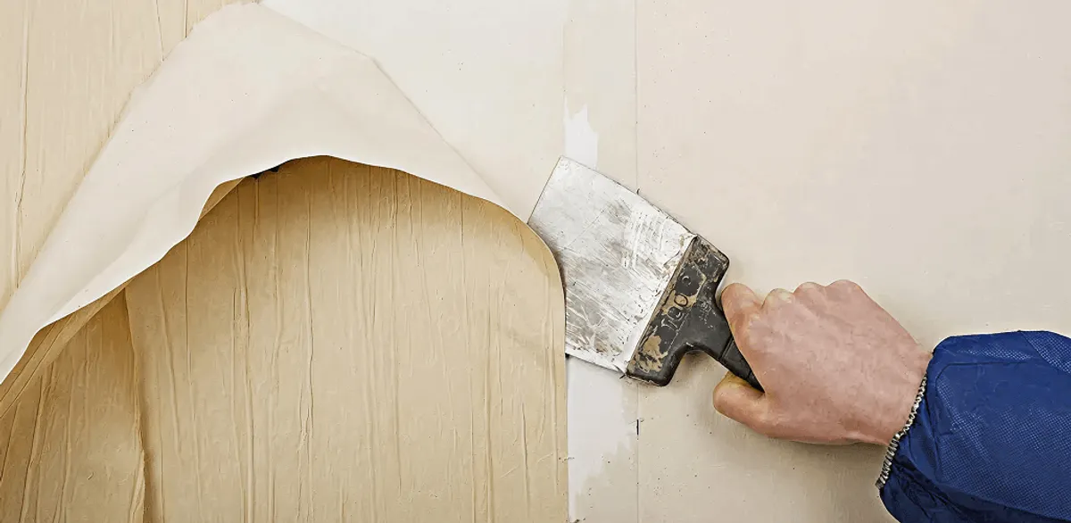 Handyman removing wallpaper with a scraper for wall preparation in Portland, OR