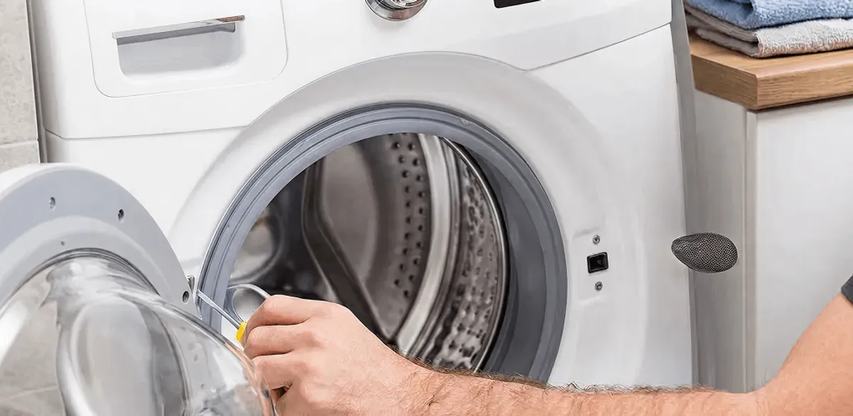 Handyman repairing a front-load washing machine and inspecting the drum in Portland, OR