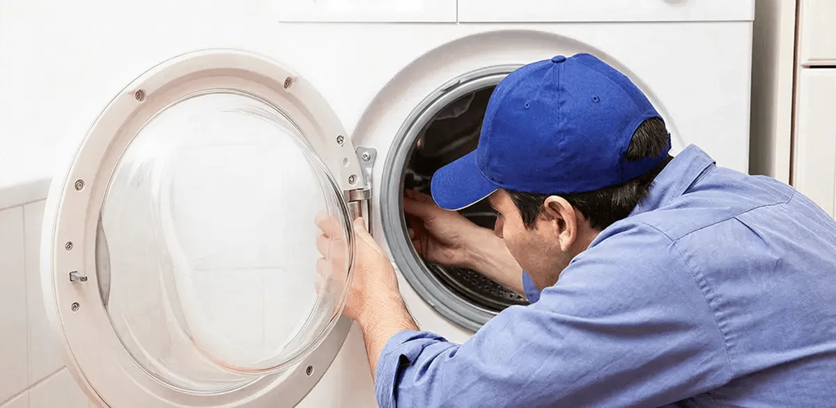 Washing machine repair handyman inspecting a front-load washer drum in Portland, OR